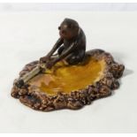 A monkey Bretby ashtray with glass eyes to monkey and moulded cigarette to the base, 16.5cm x 8cm