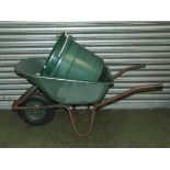 A wheel barrow and two plastic barrels