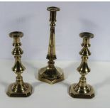 A pair of brass candlesticks and one other