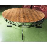 A large round pine table with wrought iron base