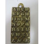 A child's alphabet brass teaching tablet inscribed verso, 'St Paul's Infant School AD 1729', 5 1/2