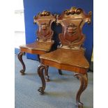 A pair of Victorian carved mahogany hall chairs, shield carved backs, on knee carved French cabriole