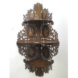 A wall hanging mahogany fretwork three tier corner display shelf with inlaid floral and figural