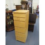 A contemporary light wood tall chest of six drawers