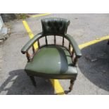 An early 20th century mahogany framed Captain style desk chair, upholstered in green leather, raised