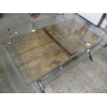 A wrought iron framed, glass topped coffee table with ornate carved door, 17.5h, 38w, 59 l