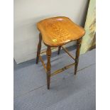 A modern oak bar stool with a carved seat, raised on turned legs