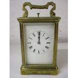 An early 20th century brass carriage clock with a visible escapement, folding handle and four