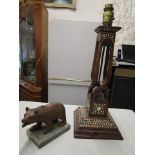 A Black Forest carved wooden bear mounted on a stone plinth and a Middle Eastern wooden table lamp