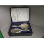 A silver brush and mirror set in a presentation box