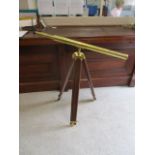 A modern brass telescope on a stained, wooden tripod stand, 40 h