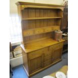 A Furniture Village pale oak dresser having two shelves, nine drawers and twin panelled doors on a