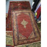 A North West Persian rug with a central medallion and geometric motifs on a red ground, 74 x 47