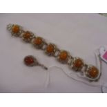 An amber coloured locket and a seven stone silver fish decorated bracelet