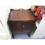 A George III mahogany pot cupboard having a galleried top with cut out handles, over a pair of doors