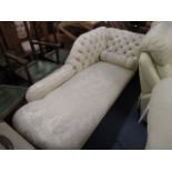 An Edwardian mahogany and cream, floral upholstered chaise longue, with a button back, and bolster