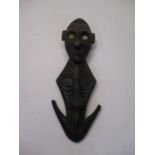 A possibly Papua New Guinea carved tribal figure with cowrie shell eyes, a diamond shaped body, a