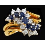 A Sapphire and Diamond Cocktail Ring claw-set seven round sapphires between two rows of brilliant-