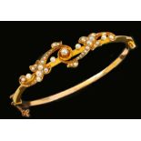 A Victorian Seed Pearl hinged Bangle, the front with scroll set graduated seed pearls, with