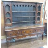 A George III oak Dresser and Rack, the base fitted three drawers above shaped frieze on cut down