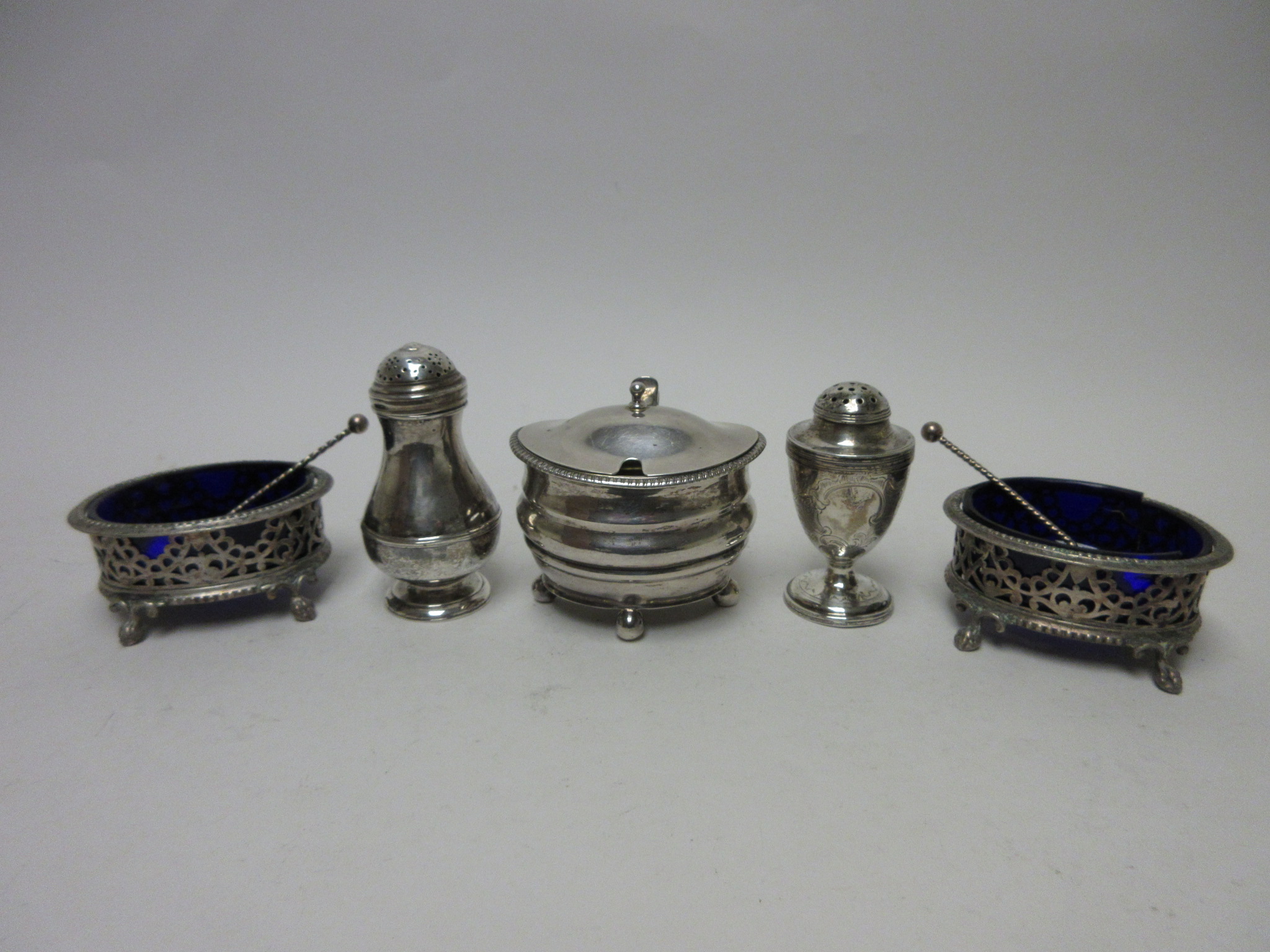 A George III silver Mustard Pot with hinged lid, beaded rim on ball feet, a George I Pepperette,