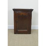 An 18th Century oak Spice Cupboard with dentil frieze above cupid's bow panelled door enclosing