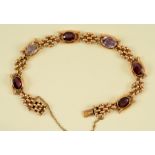 A Garnet and Amethyst Bracelet rub-over set alternating oval-cut stones in fancy links on hidden