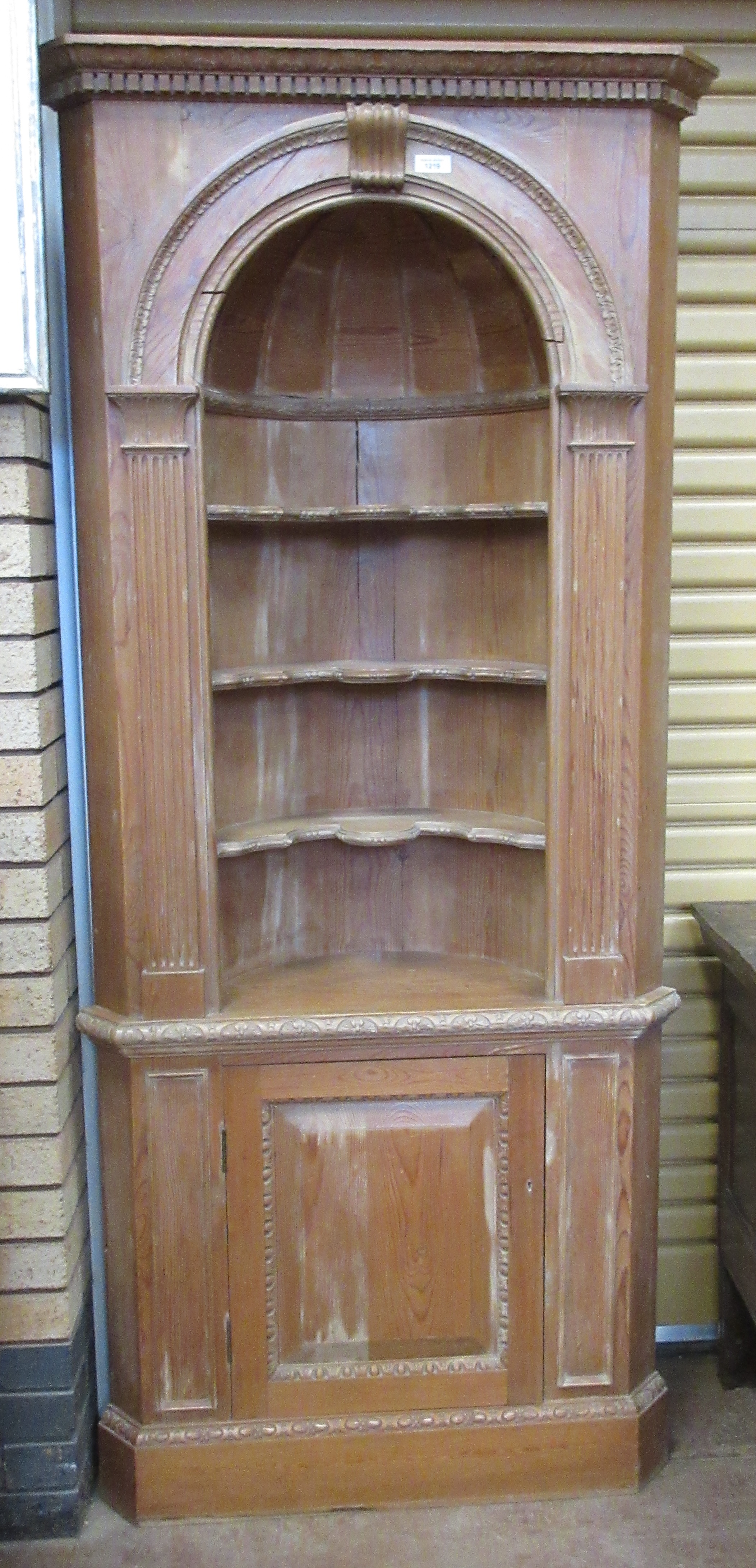 A 19th Century stripped pine Corner Cabinet with dentil frieze above domed barrel back with open