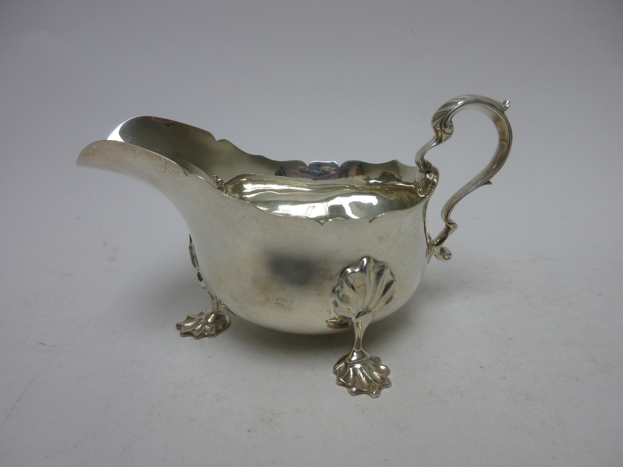 An Edward VIII silver Sauce Boat with leafage scroll handle on ornate feet, Birmingham 1936