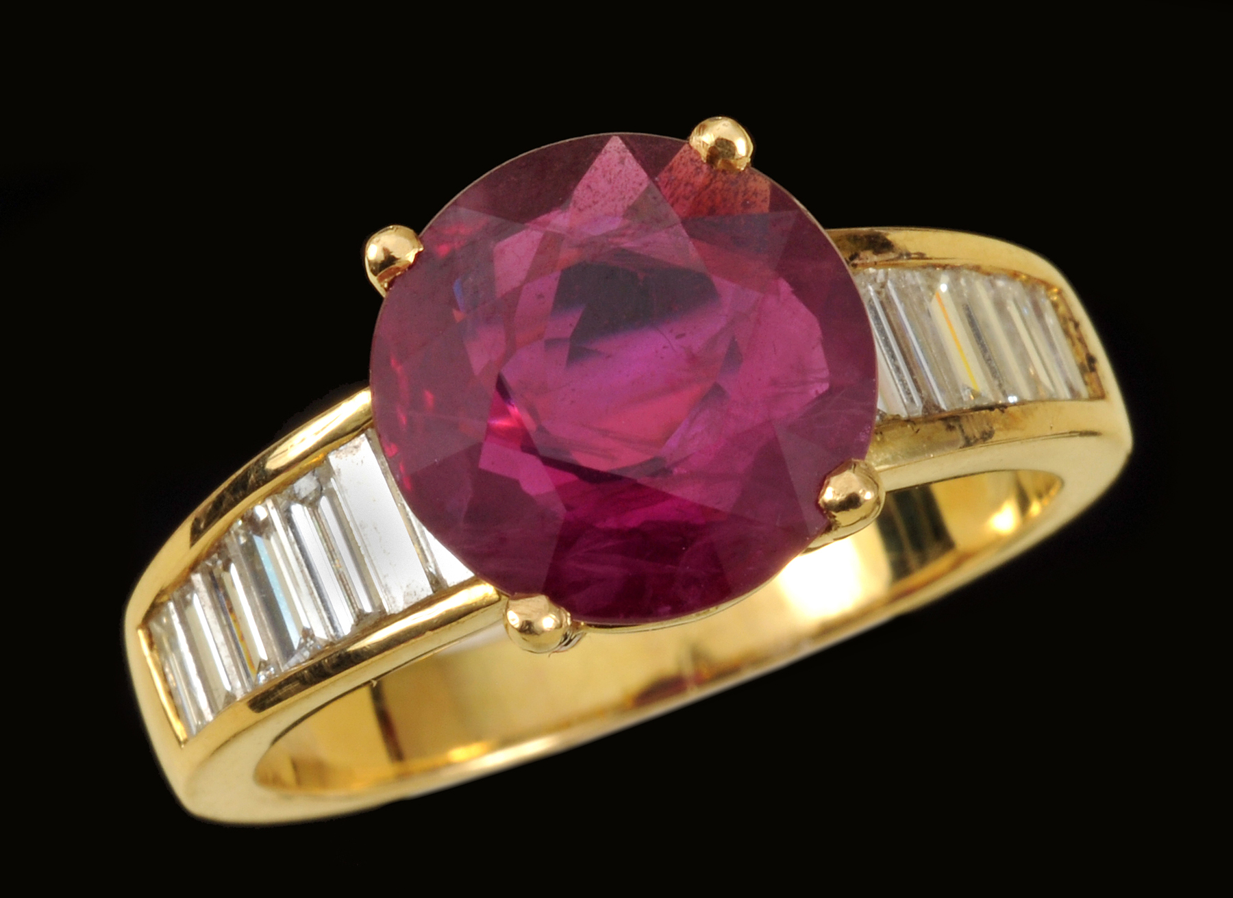 A Ruby and Diamond Ring claw-set round ruby, 3.26cts, between rows of graduated, channel-set