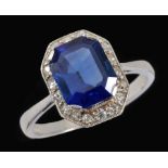 A Sapphire and Diamond Cluster Ring corner claw-set step-cut sapphire, approx 3cts, within frame