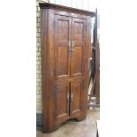 A late Georgian oak Corner Cupboard with two pairs of solid panelled doors flanked by fluted sides