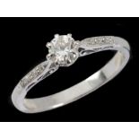 A Diamond single stone Ring claw-set brilliant-cut stone with small stones pavé-set to shoulders,