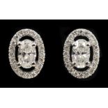 A pair of Diamond Halo Cluster Earrings each claw-set oval-cut stone within frame of pavé-set