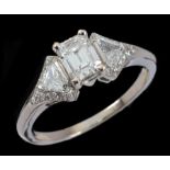 A Diamond Ring corner claw-set emerald-cut stone between two triangular-cut stones and brilliant-cut
