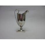 A George V silver Cream Jug of helmet shape with bright-cut decoration, shaped cartouche on square