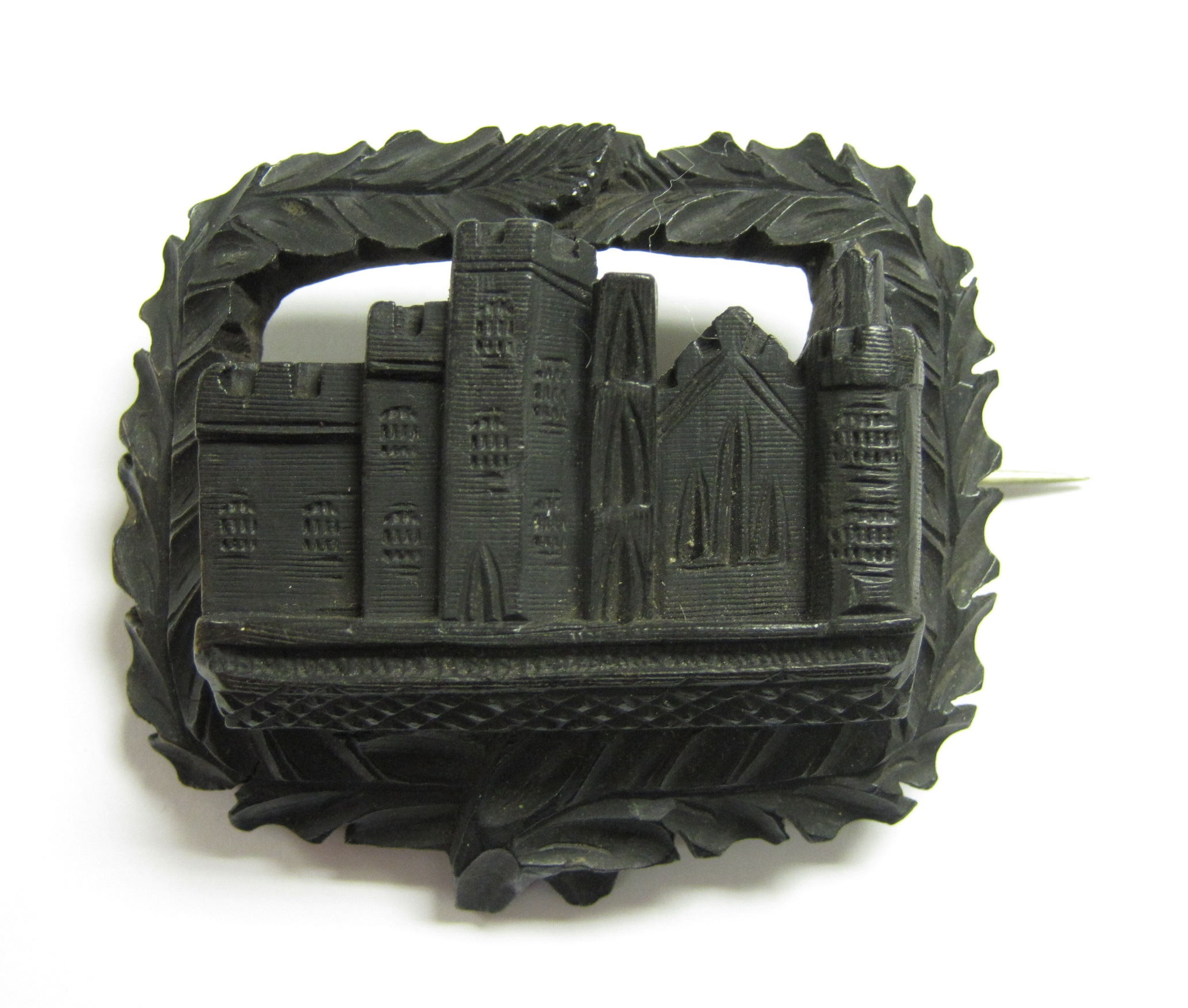 A 19th Century carved hardwood Brooch decorated with a possibly Scottish castle to the centre