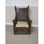 An 18th Century oak Lambing Chair with panelled back, shaped sides and arms, rope seat on square