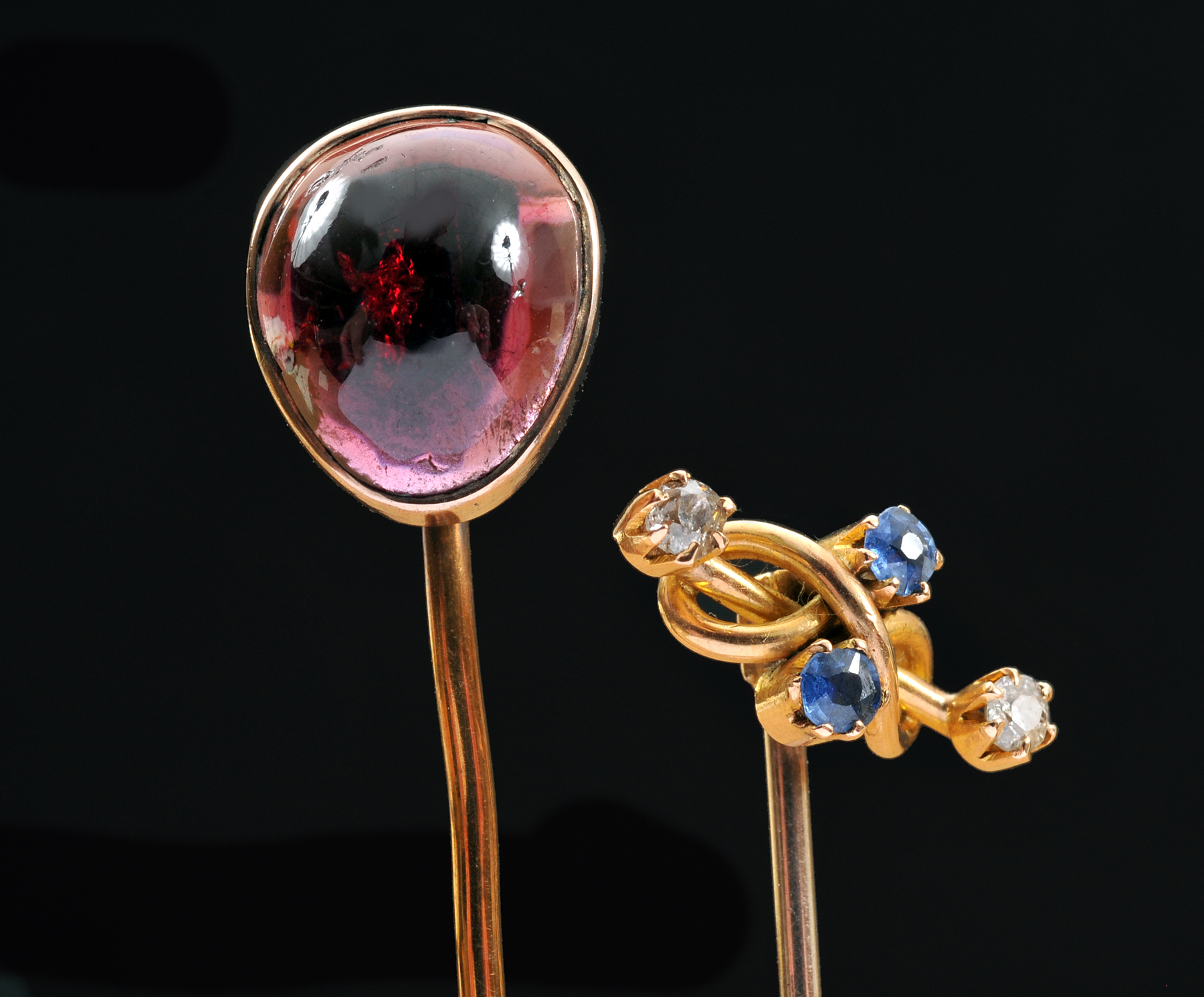 A Garnet Stick Pin set cabochon and a Sapphire and Diamond Stick Pin claw-set two round sapphires