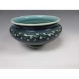 A Ruskin pottery circular Bowl with pale blue interior, pale rim, on a blue/green ground with