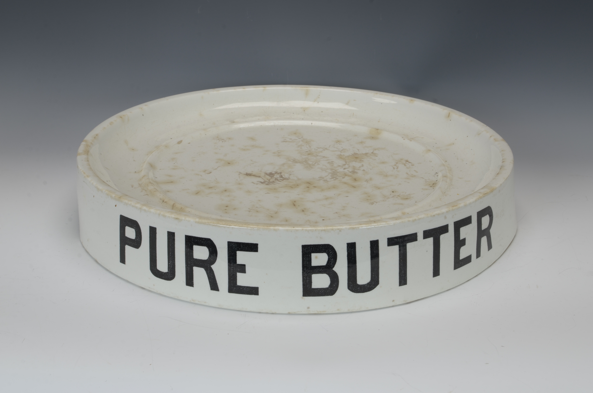 A ceramic circular Butter Slab with letters reading 'Pure Butter' on the side, 15 1/2 in D