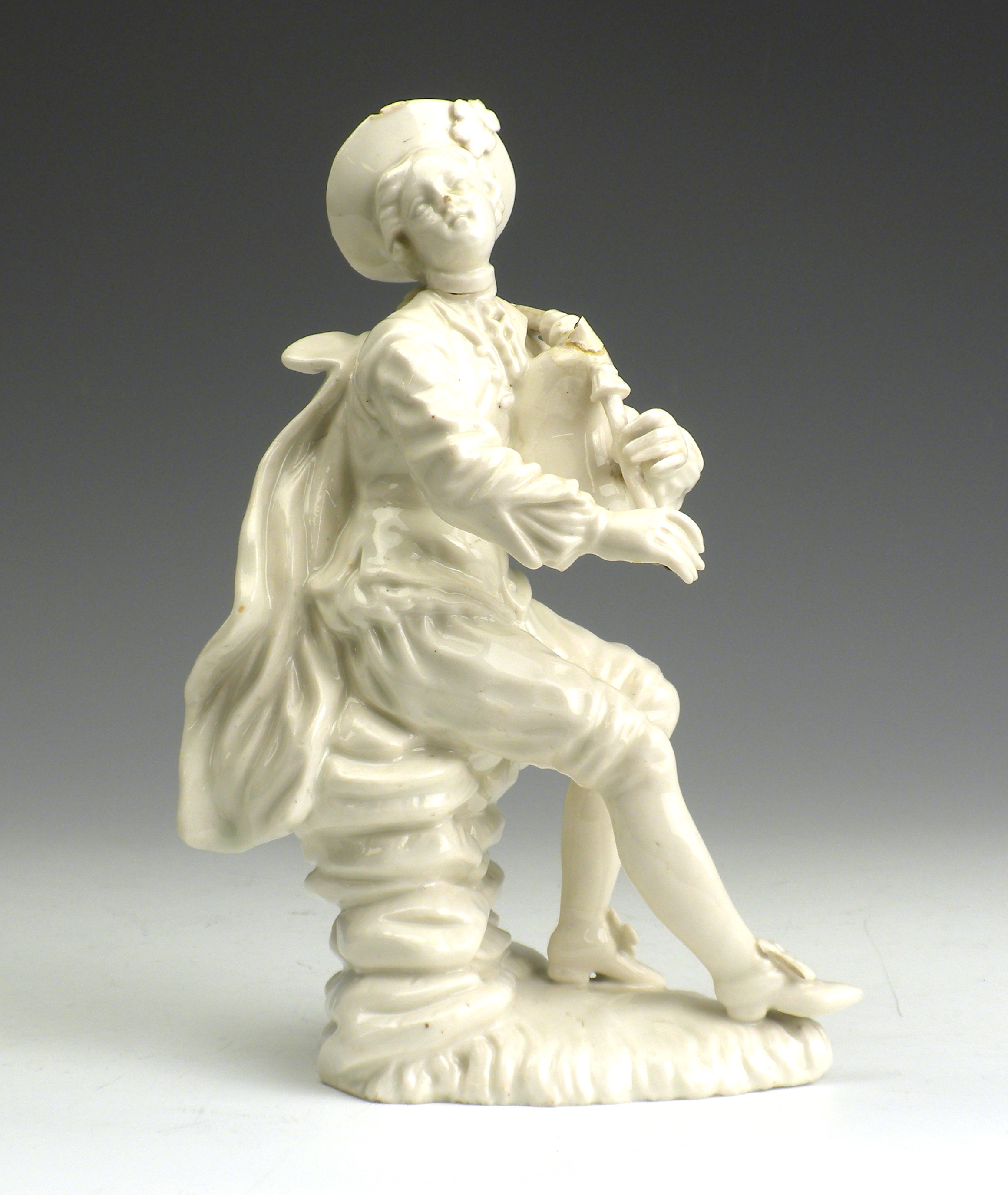 An 18th Century English porcelain Figure, c.1780, of a seated bagpiper, 7in high (repairs)