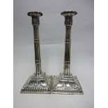 A pair of George III silver Pillar Candlesticks with leafage nozzles above cluster columns on square