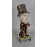 A Wayte and Ridge pottery caricature Figure of Gladstone, standing figure holding umbrella and