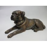 A Bretby pottery reclining Pug Dog with naturalistic detail and glass eyes, 16in, one leg A/F