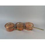 A Set of Three Small Copper Saucepans with Brass Handles and Lids