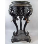 An Ebonised Anglo Indian Vase Stand with Circular Top Supported by Three Elephant Heads and Trunks.