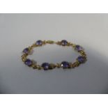 A 9ct Gold and Oval Cut Amethyst Bracelet with Stylised Butterfly Mounts. 21cm Long.
