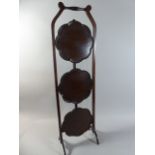 An Edwardian Mahogany Three Tier Cake Stand with Scalloped Circular Hinged Shelves.