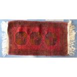 A Small Woven Woollen Patterned Rug on Red Ground.